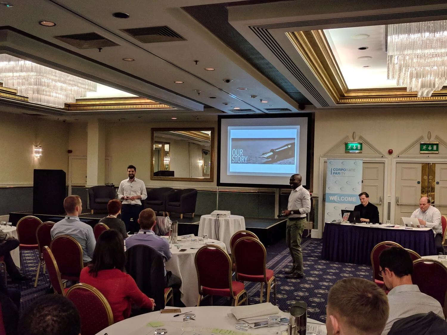 Two speakers presenting a slideshow at a conference in a smart venue