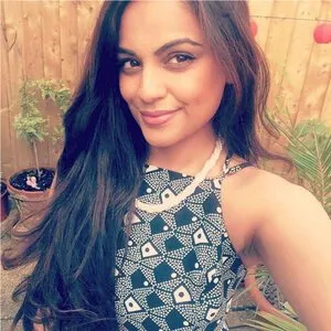 lady with long dark hair and a patterned dress smiling to camera in a garden