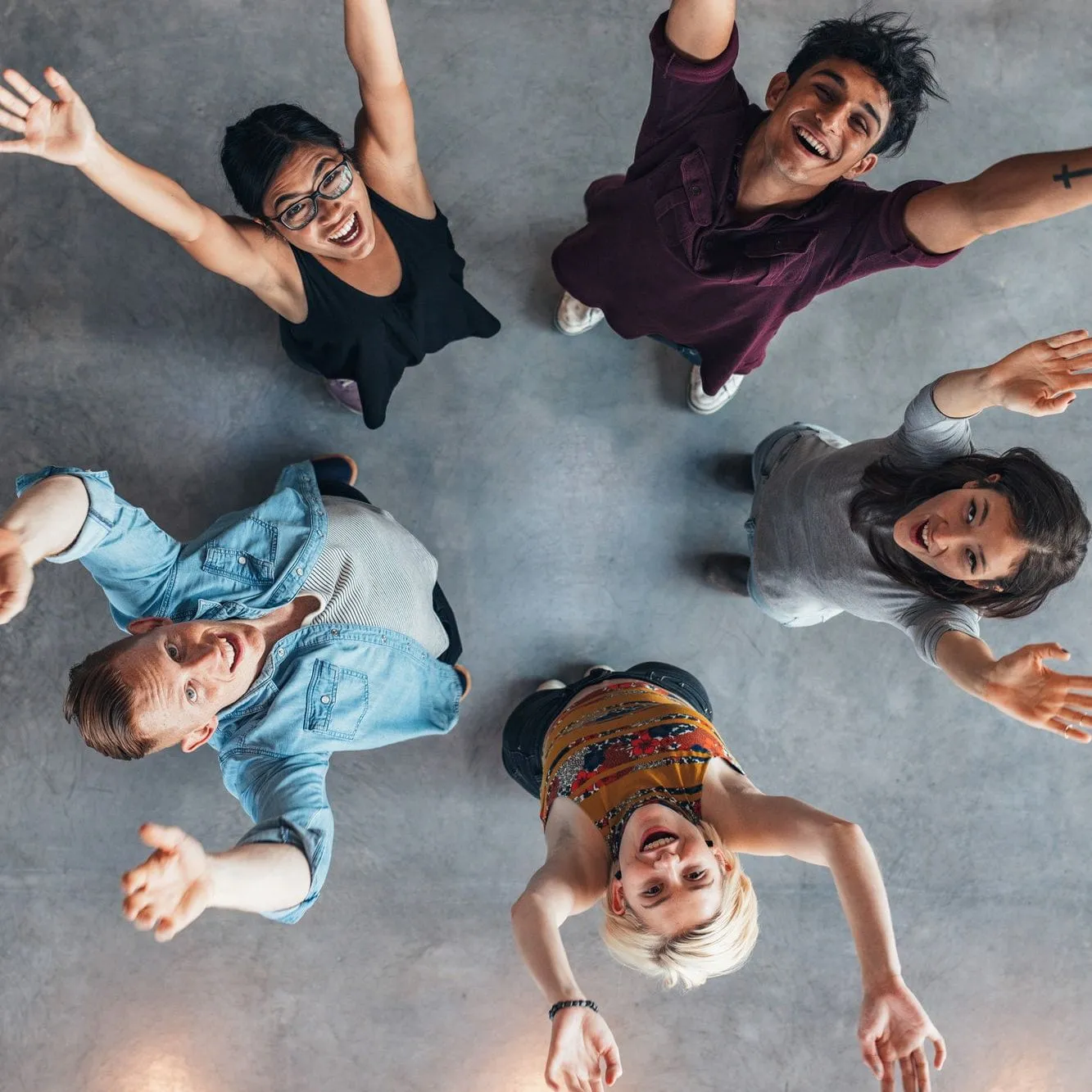looking down on a circle of happy looking students with their arms up in the air